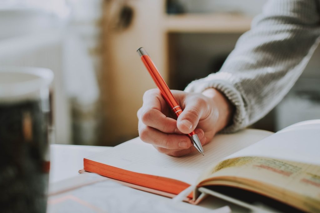 Person writing a plan in a notebook with a red pen, focused - building a 30-60-90 day plan for a new job
