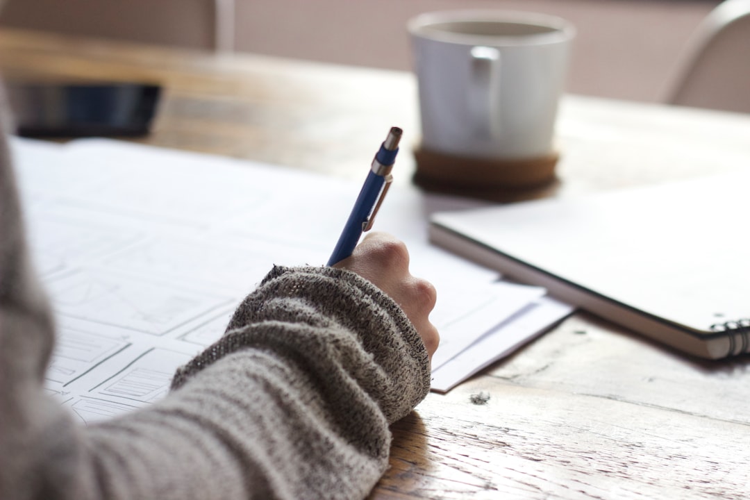Job seeker at a wooden table writing a brief to prepare their job references before a reference check.