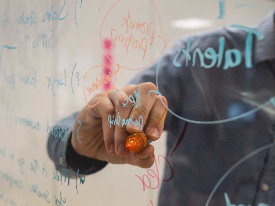 A project manager mapping out a delivery plan with diagrams on a glass whiteboard, focused on outcomes rather than tracking tasks.