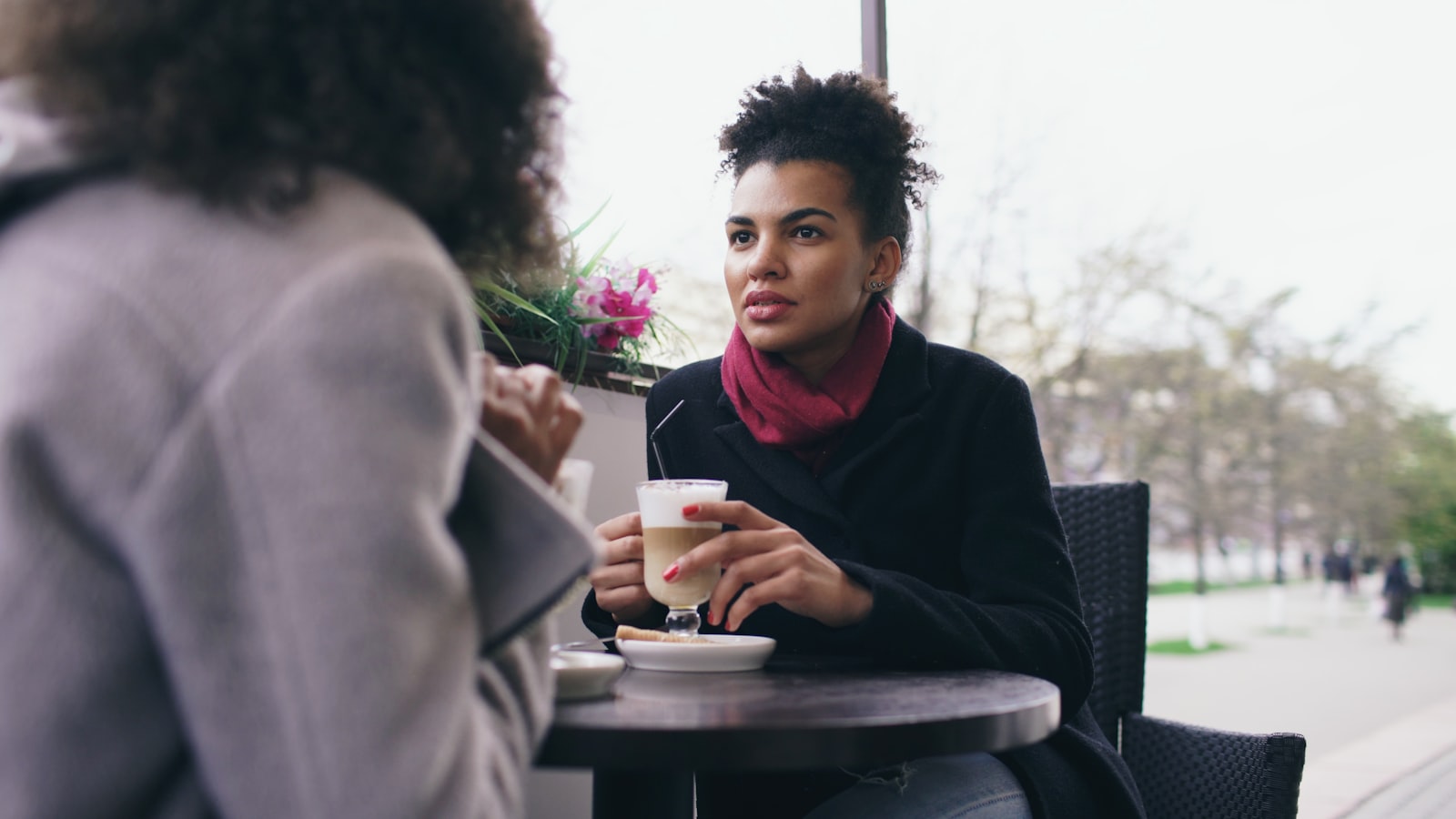 Two people in a focused one-on-one conversation at a table, one listening closely while the other speaks - a candidate evaluating a future manager during an interview.