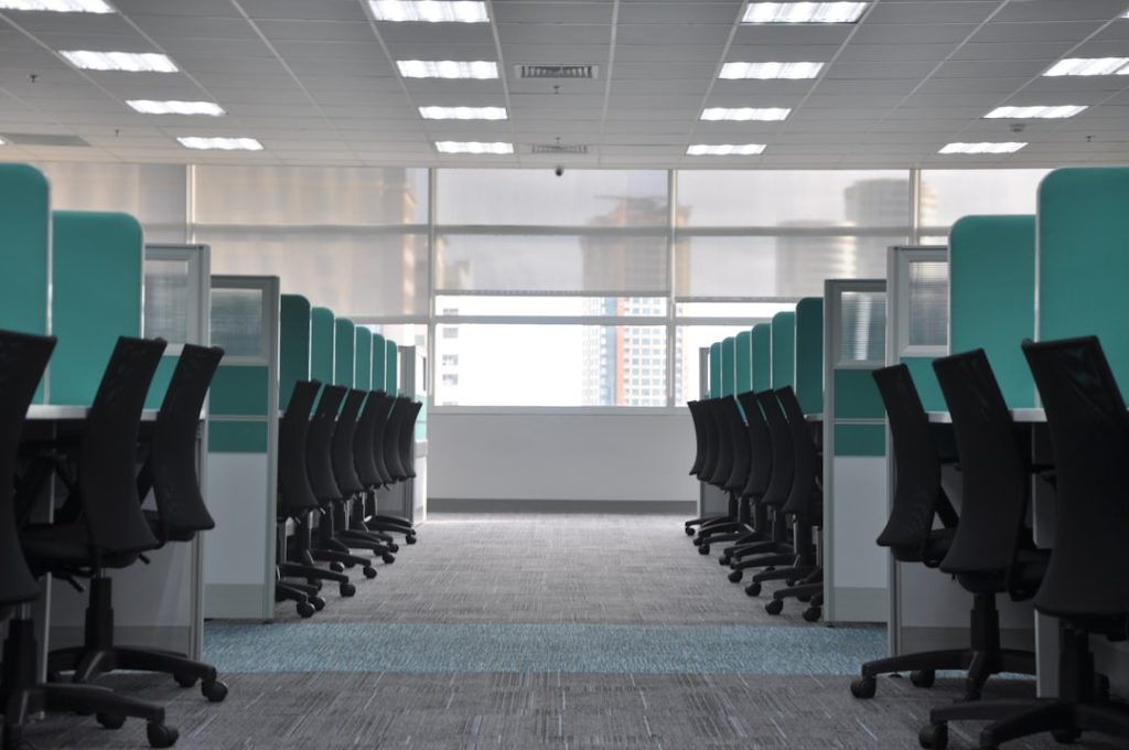 Rows of empty office chairs at vacant cubicles, suggesting a workplace thinned out by layoffs