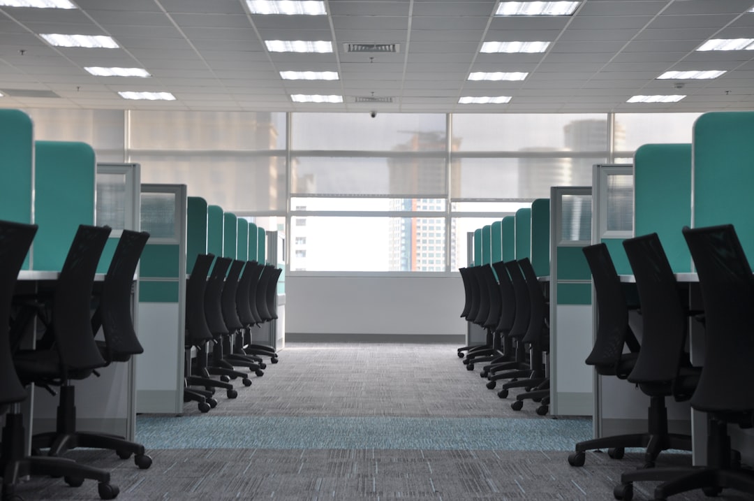 Rows of empty office chairs at vacant cubicles, suggesting a workplace thinned out by layoffs