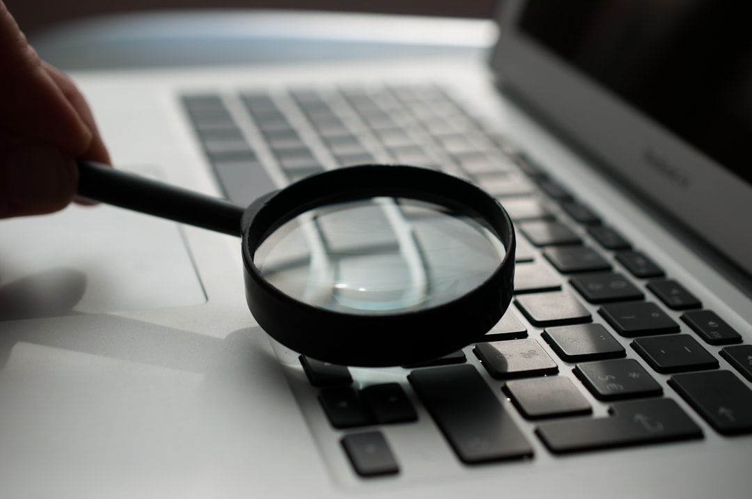 A magnifying glass resting beside a laptop, standing in for searching a database precisely rather than scrolling it.
