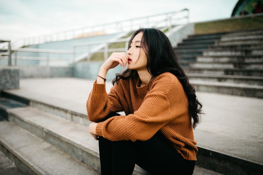 A job candidate pauses with her hand near her mouth, choosing her words carefully during an interview.