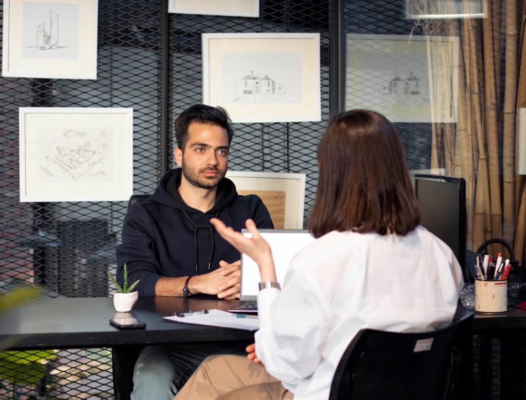 A job candidate answering a question across a desk from an interviewer during a one-on-one job interview.