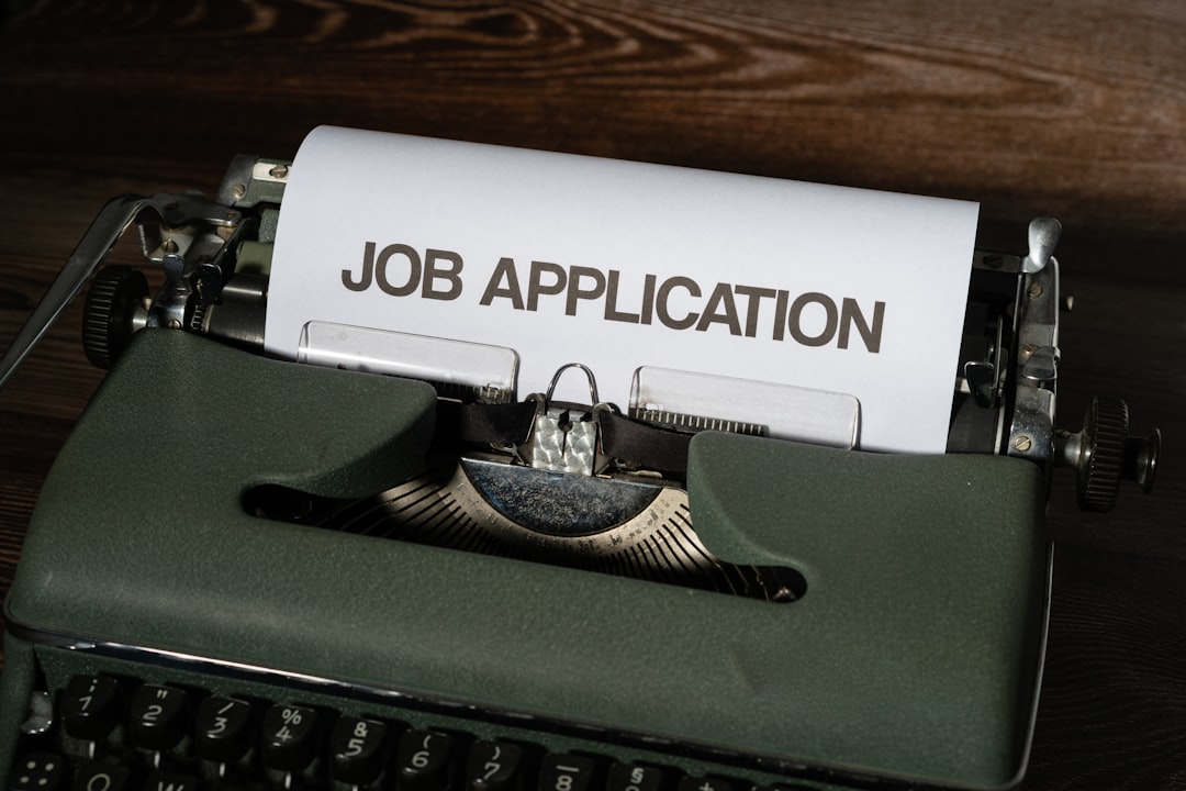 A vintage green typewriter with a sheet of paper rolled into it, reading JOB APPLICATION in large capital letters.