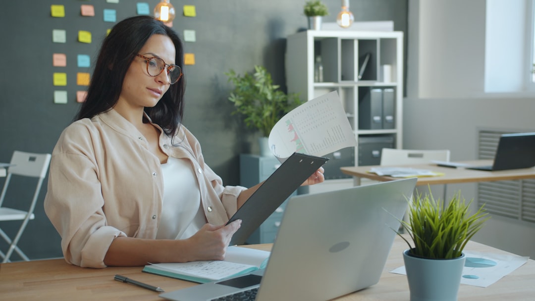 A professional at an office desk reviewing a document of charts and figures, checking the numbers before a compensation conversation.