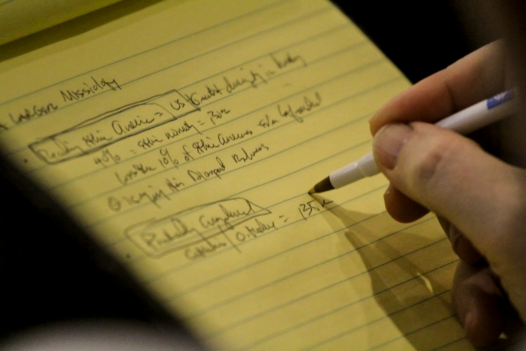 Close-up of a hand writing notes and figures on a yellow legal pad, with results boxed and a dollar total at the bottom